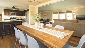 A modern kitchen with dark cabinets, a wooden dining table, and a chandelier.