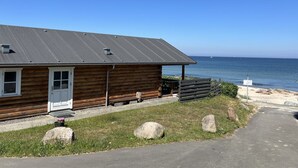 A wooden cabin with a metal roof, a small porch, and a view of the ocean.