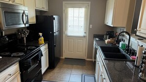 A kitchen with white cabinets, a black refrigerator, a stove, and a microwave. - Amazing 3-bedroom home with 2 full baths. Spacious fenced backyard. WiFi present (Fort Smith)