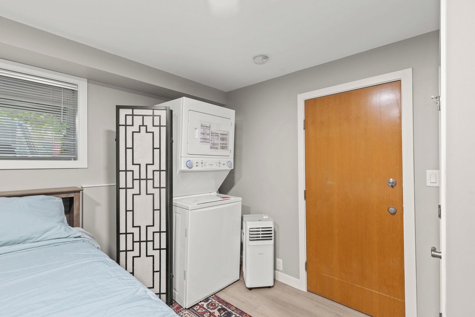 A bedroom with a bed, a wardrobe, a heater, and a door.