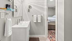 A modern bathroom with a vanity, two mirrors, a towel rack, and a shower area.