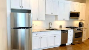A modern kitchen with white cabinets, stainless steel appliances, a dishwasher, and a microwave.