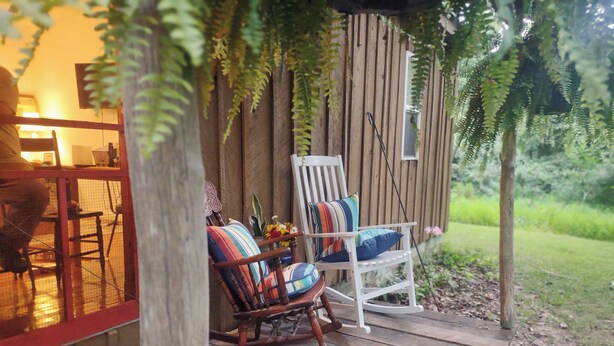 A wooden deck with two rocking chairs, one with colorful cushions and one with a striped cushion. - Delightful Cabin near a wildlife refuge, 6 miles to Carbondale Illinois. (Carbondale)