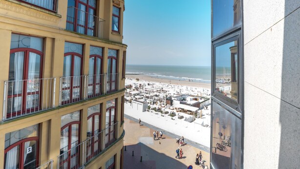 Hotel alto com várias varandas com vista para a praia.