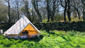 A tent set up in a grassy area with a stone wall in the background. - Bell Tent , Carreglwyd Estate, Anglesey (Llanfaethlu,)