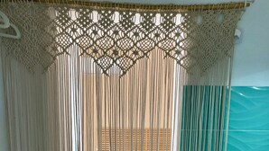 A bathroom with a macramé curtain, a wooden bench, a wicker basket, and a white sink. - Villa Aroi just a stone's throw from the sea! (Sicilia)