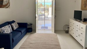 A living room with a blue sofa, a white dresser, and a large window. - Villa Aroi just a stone's throw from the sea! (Sicilia)