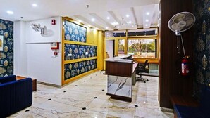 A hotel lobby with a reception desk, seating area, and a large window offering a view. - Hotel Travaasa Inn (Jaipur)