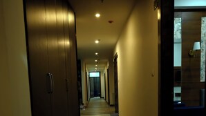 A hotel hallway with a marble floor, wooden doors, and recessed lighting. - Hotel Travaasa Inn (Jaipur)