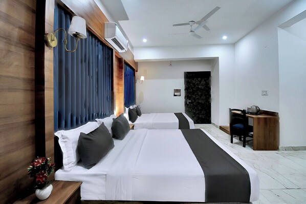 Une chambre d’hôtel avec deux lits, un bureau et un ventilateur de plafond.