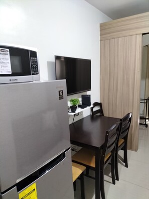 Una kitchenette compacta con refrigerador, microondas y televisión de pantalla plana.
