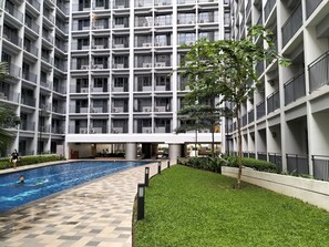Un moderno edificio de apartamentos con varios balcones, una piscina y un césped bien cuidado.