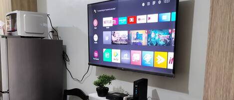 Una cocina moderna con un televisor de pantalla plana montado en la pared que muestra diversas aplicaciones de transmisión.