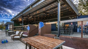 Een terras met tafels en stoelen, een overdekte patio en een gebouw met een bord.