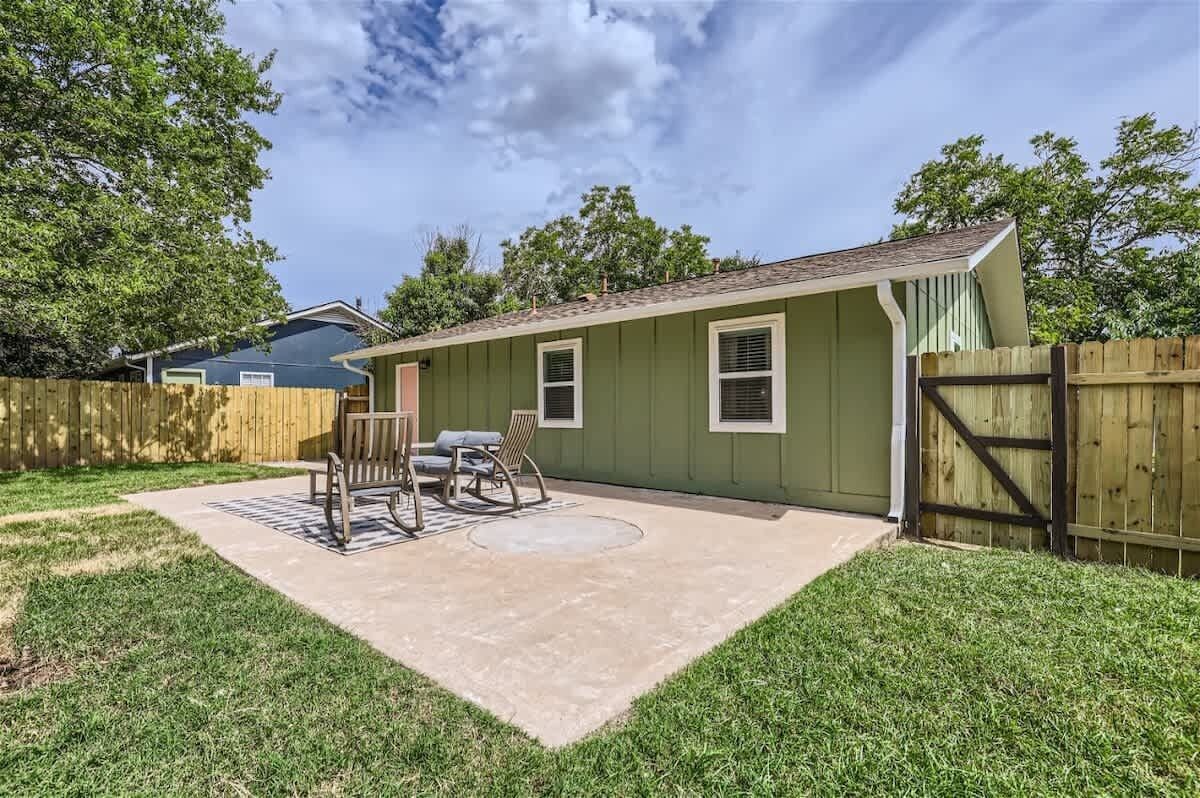 A backyard with a patio, a wooden fence, and a house.