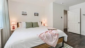 Een slaapkamer met een bed, een plafondventilator, twee wandlampen en een deur.