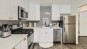 Een moderne keuken met witte kastjes, roestvrijstalen apparatuur en een backsplash van mozaïektegels.