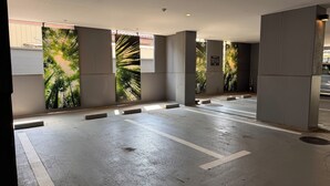 A parking garage with concrete pillars, white painted lines, and large vertical murals of trees. - HOTEL EN (Yokohama)