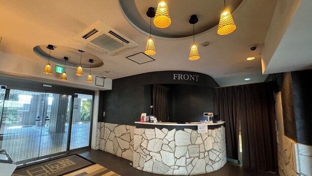A hotel reception area with a stone wall, a reception desk, and hanging pendant lights. - HOTEL EN (Yokohama)