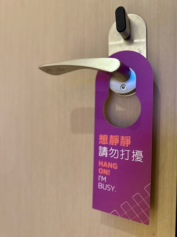 Une porte avec une enseigne violette suspendue sur laquelle on peut lire : « NE DÉRANGEZ PAS ! JE SUIS OCCUPÉ. »