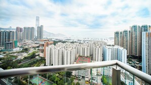Um edifício alto com vista para um horizonte urbano, incluindo outros edifícios altos e uma massa de água ao longe.