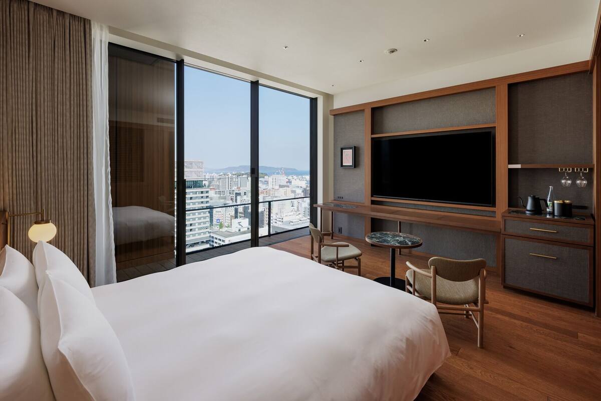 Une chambre d’hôtel avec un grand lit, une télévision, un bureau et une vue sur la ville.