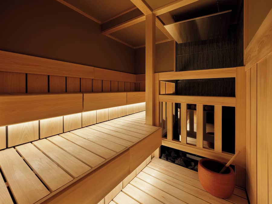 A wooden sauna with benches and a stone basin.