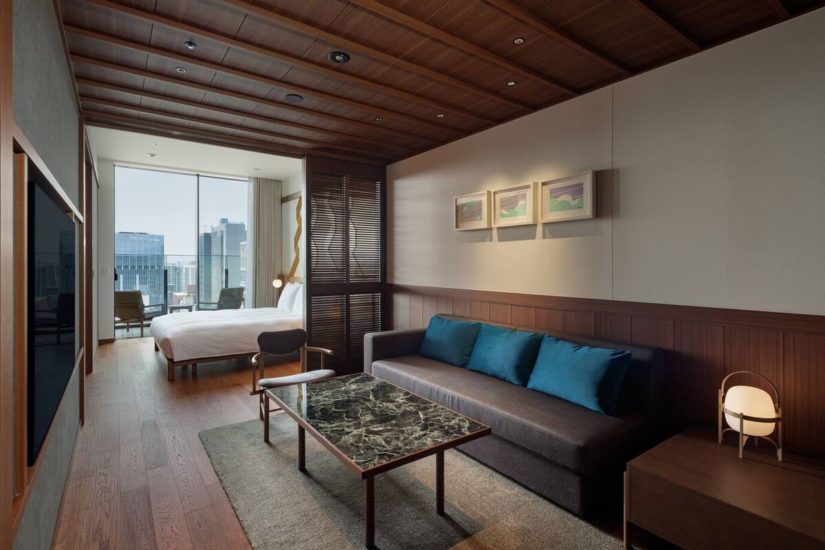 Une chambre d’hôtel moderne équipée d’un lit, d’un canapé, d’une table basse et offrant une vue sur la ville.