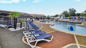 Ett poolområde med solstolar, en liten pool och en vattenrutschkana.