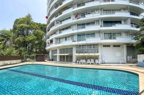 Guests can enjoy a pool and lounge by the water, surrounded by trees and a fence.