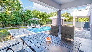 Un espace extérieur abrité comprenant une piscine, des chaises longues et une table avec un saladier.