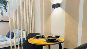 Een eetruimte met een ronde houten tafel, zwarte stoelen en een wandlamp.
