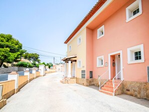 Ein pinkfarbenes Gebäude mit steinernen Fundament, weißer Tür und kleinem Fenster.