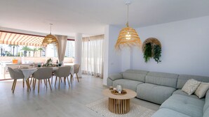 Una sala de estar moderna con un sofá seccional gris, una mesa de centro redonda y un comedor con una mesa y sillas.