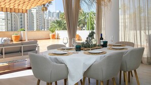 Comedor con una mesa preparada para cuatro personas, con individuales tejidos y una botella de vino.