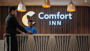 A hotel reception desk with a sign reading "Comfort INN" and two attendants. - Comfort Inn Elite Goa (Panaji)