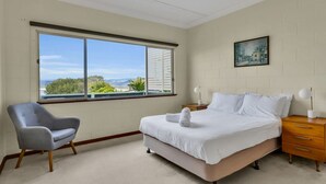 A bedroom with a large window, a bed, a chair, and a nightstand. - Cliffhanger - Pet Friendly! (Merimbula)