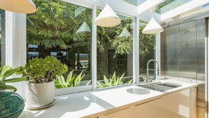 A modern kitchen with a large window, white countertops, and a sink. - Lake 54 - Beautiful Views, Perfect Location! (Merimbula)