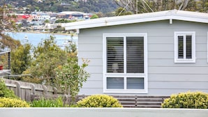 A single-story house with a large window and a view of the water and town in the background.