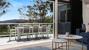 A balcony with a table and chairs, a sofa, and a view of the landscape.