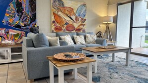 Un salon moderne avec un canapé gris, une table basse et un grand tableau abstrait accroché au mur.