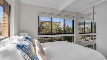 A bedroom with a large bed, multiple windows, and a view of the outside.