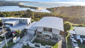 Una casa moderna de dos pisos con un balcón amplio, rodeada de vegetación exuberante y vista al mar.
