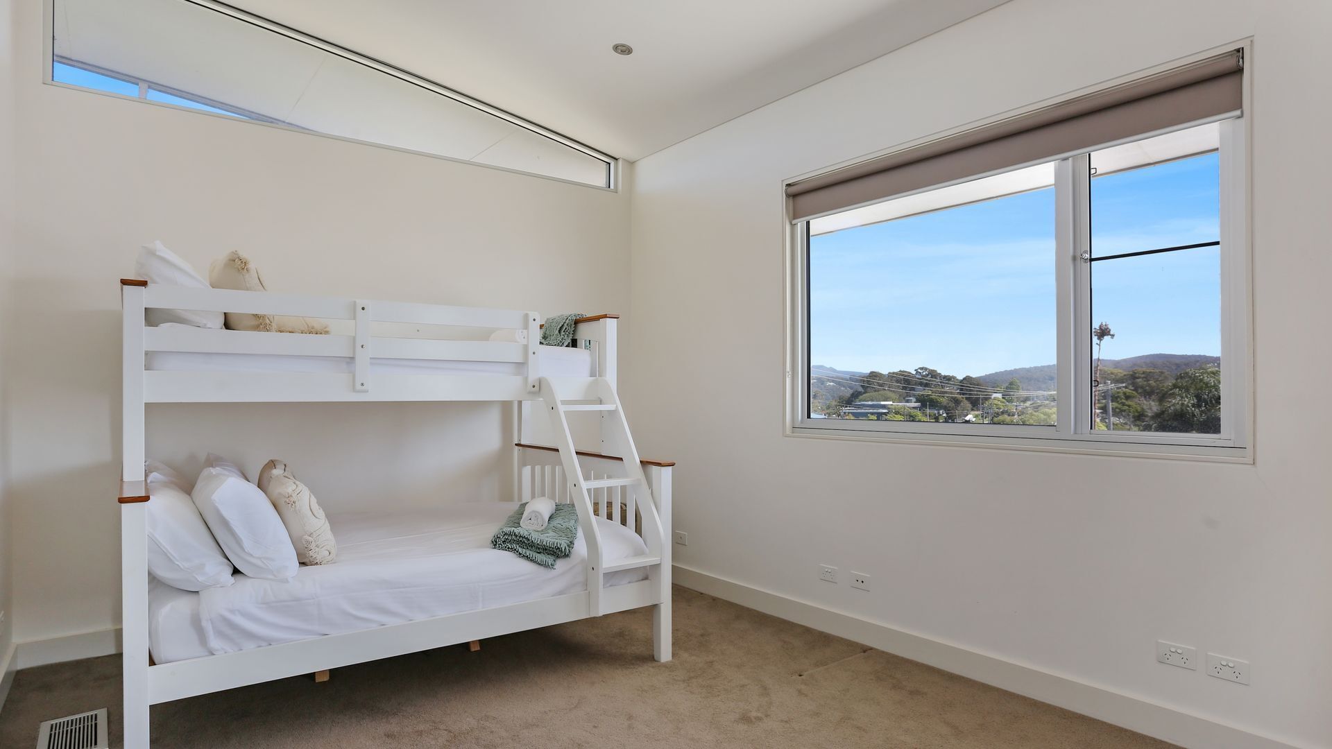 A bunk bed room with a window offering a view of a hilly landscape.