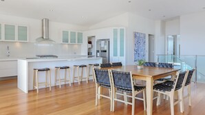 Una cocina moderna con armarios blancos, una isla central y taburetes de bar.