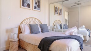 Un dormitorio con una cama grande, una mesita de noche con una lámpara y un espejo en la pared.