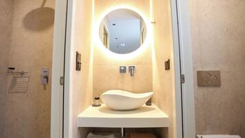 A bathroom with a round mirror, a white sink, and a towel rack.