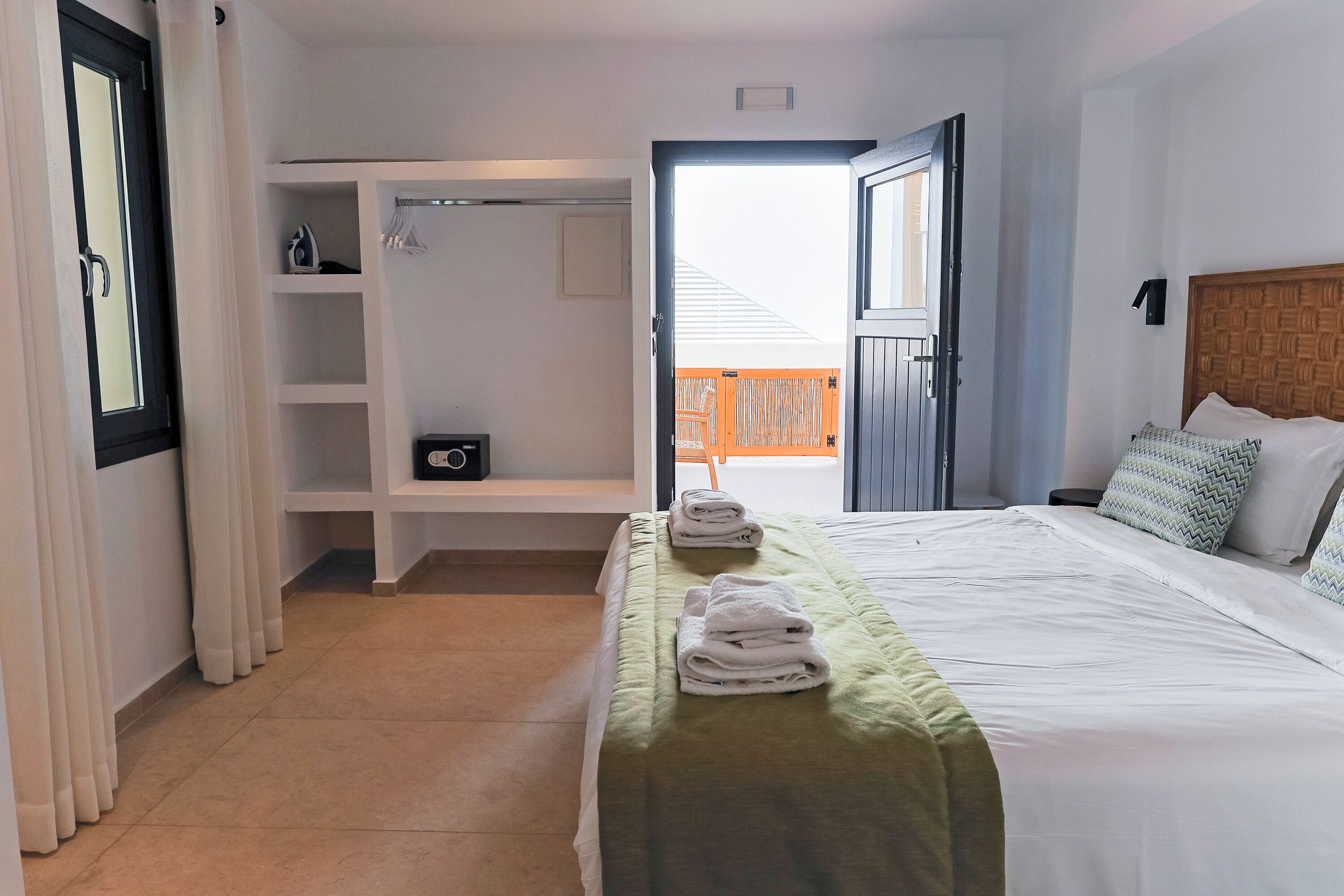 A hotel room with a neatly made bed, a walk-in closet, and a view of the outside.