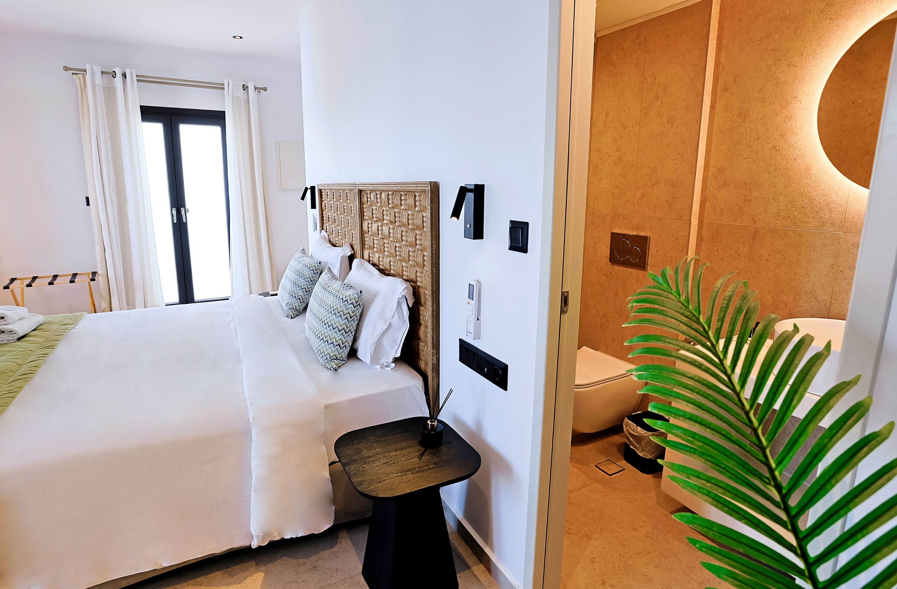 Une chambre d’hôtel avec un lit, une table de chevet et une plante en pot.