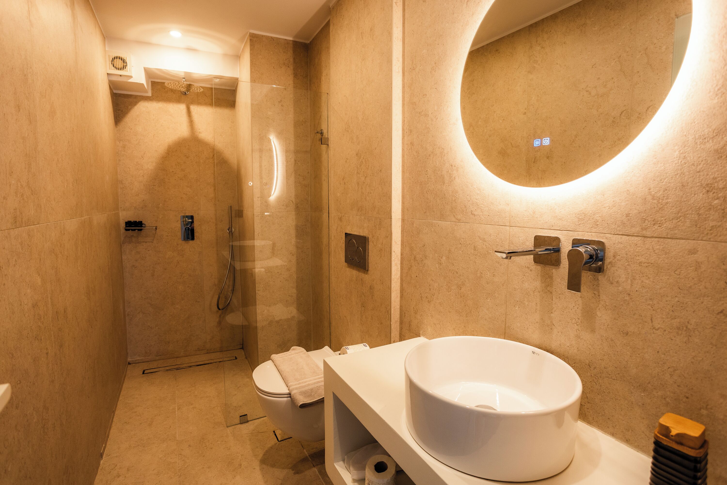 Un baño moderno con lavamanos grande, inodoro y cabina de ducha con mampara de vidrio.